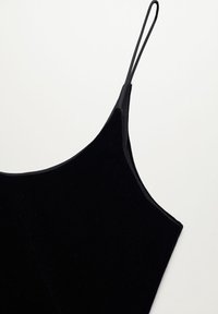 Camisole en velours noir avec fines bretelles, texture lisse et silhouette cintrée avec un décolleté arrondi. Aucun élément métallique ni motif visible.