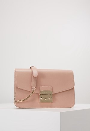 Lyserød tekstureret læder clutch taske med en guldfarvet metal lås og kædedetalje, placeret på en hvid podium mod en ensfarvet baggrund.