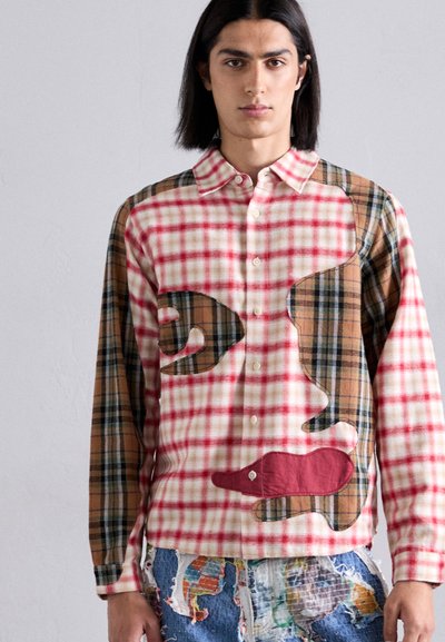 Checkered shirt featuring mixed patterns in red, white, and brown with geometric cutouts, buttoned collar, and a relaxed fit.