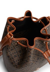 Καφέ και μαύρη τσάντα κουβάς με δερμάτινες λεπτομέρειες, κλείσιμο με κορδόνι και μονό ιμάντα ώμου, εμφανιζόμενη ανοιχτή από πάνω.