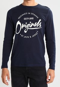 Marineblaues Langarmshirt mit rundem Halsausschnitt. Mit weißem Grafiktext: "DESIGNED IN CPNHGN," "ESTD 1990," und "Originals by JACK & JONES."