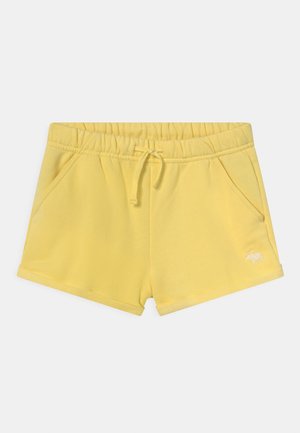 Short jaune à taille élastique avec cordon, poches latérales et petit logo blanc brodé sur la jambe gauche.