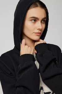 Black hooded sweatshirt with a zipper, ribbed cuffs, and a soft texture. The hood is lined, and the fabric shows slight wear.