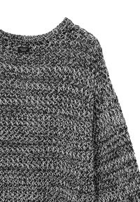 Maglione lavorato a maglia in bianco e nero con collo rotondo. Motivo testurizzato su tutta la superficie e un'etichetta con la scritta "ZERO WASTE DESIGN" sul collo.