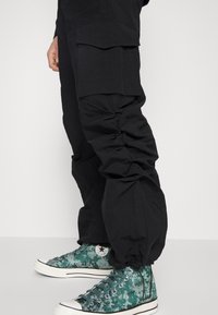 Pegador STACKED PANTS UNISEX - Calças cargo - black