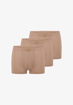 Tre beige herre boxershorts med elastiske linninger og forreste pose, arrangeret i en trappetrinsrække.