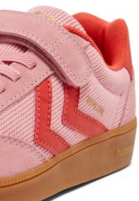 Rosa sneakers med en texturerad övre del i tyg, mockadetaljer, djärva röda överlägg, en kardborreband och en sula av gummigummi.