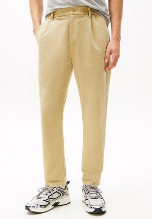 Khaki chino's met een relaxte pasvorm, een elastische tailleband en zijzakken. Gepaarde met witte en zilveren sport sneakers.