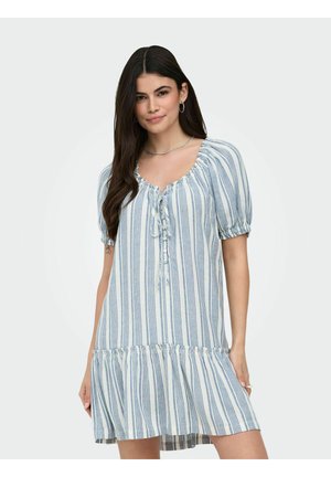 Donna con capelli lunghi e scuri che indossa un vestito a maniche corte a righe verticali bianche e blu con scollo arricciato e orlo arricciato.