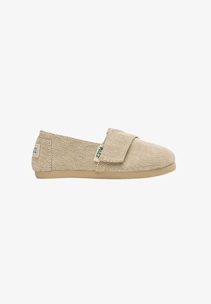Scarpa beige intrecciata slip-on con suola piatta in gomma e fascia in tessuto sul collo del piede, con piccole etichette del logo verdi sul lato e sul tallone.