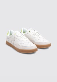Des baskets blanches en cuir et en suède, avec un embout perforé, des accents verts au niveau du talon et une semelle en caoutchouc gomme.