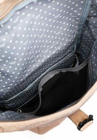 Tan bag interior features a light gray polka dot lining, multiple compartments, including a mesh pocket and a zippered section.