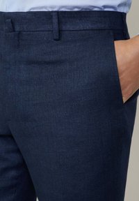 Pantaloni blu navy realizzati in tessuto testurizzato, caratterizzati da un taglio dritto, tasche laterali e una finitura liscia in vita.