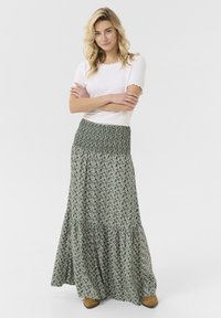 Maxi krilo s cvetličnim vzorcem v zelenih in vijoličnih tonih. Raztegljiv nabran pas, večplastna zasnova in lahek material.