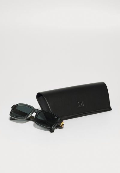 Sunglasses with dark green lenses, rectangular black frame, and gold accents, alongside a black leather case with a subtle logo.
