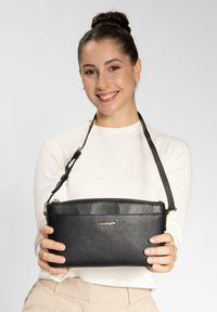 Borsa a tracolla in pelle nera con superficie texture, chiusura con zip e tracolla regolabile; presenta un marchio dorato sulla parte anteriore.