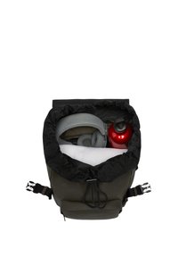 Sac à dos vert foncé avec un dessus noir à cordon, contenant des écouteurs gris, une bouteille d'eau rouge avec un couvercle noir, et un tissu texturé blanc.