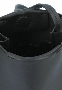 Sac en cuir noir en forme de seau avec une base ronde, texture lisse et fines bretelles, présenté avec un design intérieur minimaliste.
