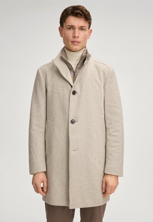 Beige Karomuster-Mantel mit Reverskragen, drei Knöpfen, zwei Seitentaschen und strukturiertem Finish. Trägt man über einem hellen Rollkragenpullover.