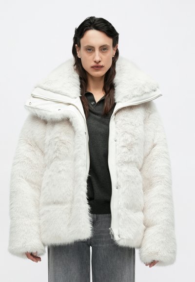 Veste matelassée en fausse fourrure blanche avec une grande capuche, une fermeture éclair et des détails à boutons. Elle présente une surface texturée et duveteuse ainsi que des manches larges.