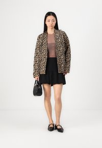 Leopard print jacket, brown top, black ruffled skirt, black handbag, and black flat shoes. Sleek textures and contrasting colors are featured.