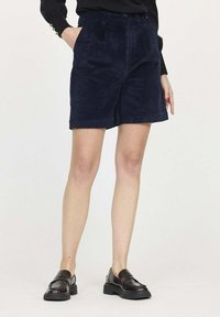 Shorts en velours côtelé bleu marine avec une finition texturée, dotés de poches latérales, d'une fermeture par bouton et glissière, et d'une coupe droite au-dessus du genou.