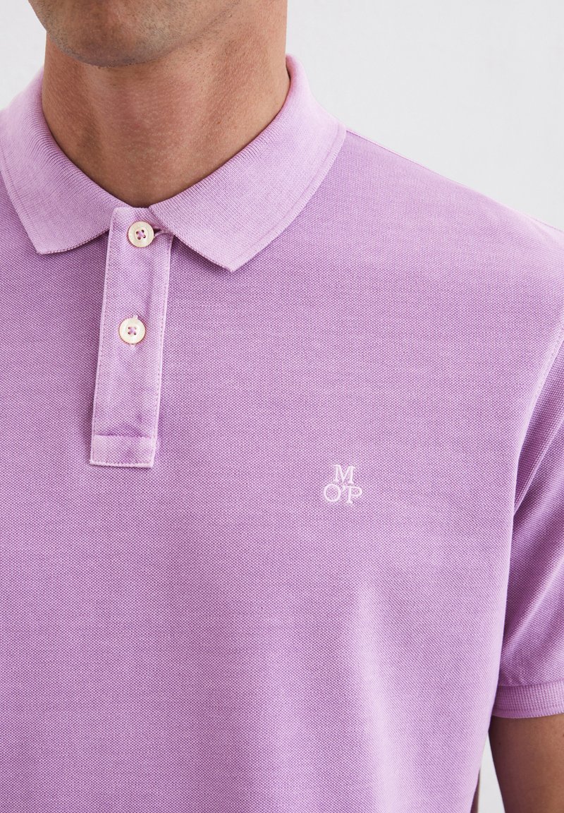 Liliowa koszulka polo wykonana z fakturowanej tkaniny, z dwoma guzikami i małym haftowanym logo 'M OP' na piersi.