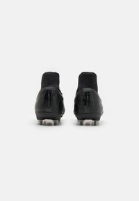 Des chaussures de football noires en matériau synthétique lisse, avec un design à haute cheville, des accents texturés et des crampons coniques pour une meilleure adhérence.