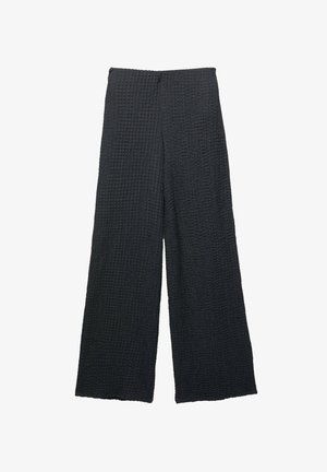Schwarze weite Hose aus strukturiertem, gesteppetem Stoff. Mit hoher Taille und lockerer, fließender Schnittführung. Keine sichtbaren Beschläge oder Verzierungen.