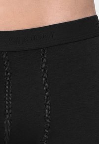 Boxer-briefs noirs en tissu doux, dotés d'une large ceinture élastique avec logo de marque en relief et détails de couture contrastés.