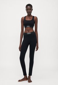Sort atletisk crop top og leggings lavet af strækbart stof, med en mærket elastisk talje og et rent, minimalistisk design.