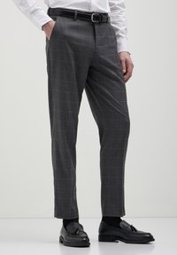 Grau gestreifte Hosen mit slim Fit, gefertigt aus glattem Stoff, mit einem schwarzen Gürtel und kombiniert mit schwarzen Slippern.