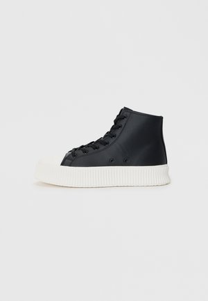Zwarte hoge sneakers van glad materiaal, met een witte rubberen zool met ribbelstructuur en een klassieke vetersluiting.