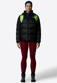Fekete pufftáska cipzárral az elején, élénk zöld hátizsák, burgundi leggings és fekete csizmák. Simaság jellemzi, szigetelt dizájn, minimális márkázással.