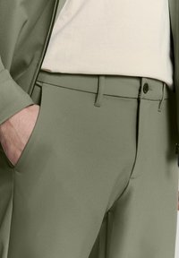 Grüne maßgeschneiderte Hose aus glattem Stoff, mit slim fit, flachem Front, Seitentaschen und Knopfverschluss.