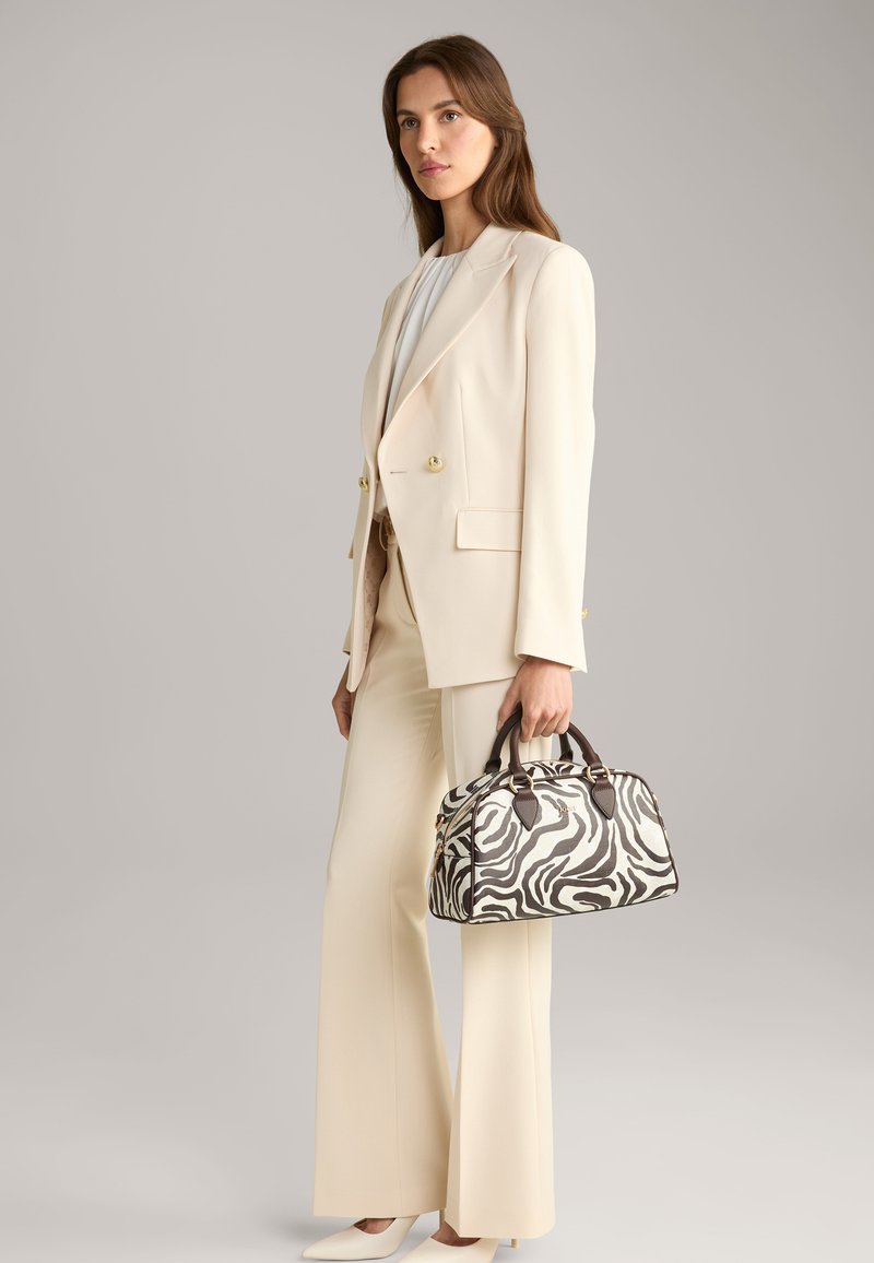 Costume beige sur mesure avec un pantalon à larges jambes, associé à un sac à main à imprimé zèbre avec des accents foncés et des finitions dorées.