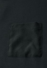 Černá látka s přišitou kapsou vyrobenou z mírně odlišné texturované černé látky, umístěná ve středu rámu.