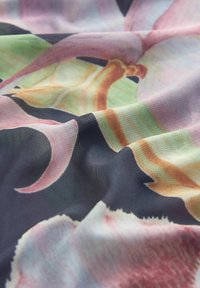 Textilní látka s květinovým vzorem v růžových, zelených a oranžových odstínech na tmavém pozadí, vykazující hladkou texturu a složité detaily.