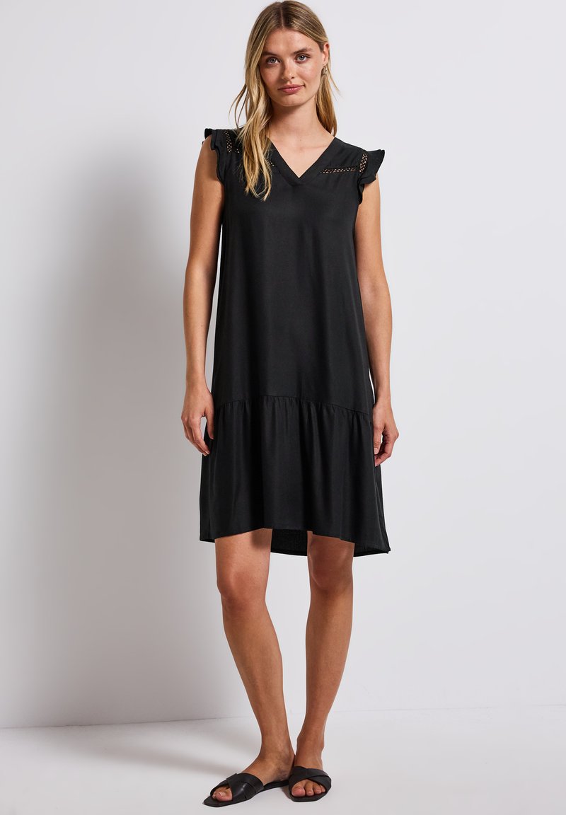 Schwarzes kurzes Kleid mit kurzen Ärmeln, V-Ausschnitt, Rüschenschultern und einem gestuften Saum. Glattes Material mit lockerem Schnitt, das bis zur Mitte des Oberschenkels reicht.