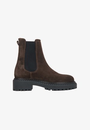 Brown suede Chelsea boots with black elastic side panels, a rounded toe, and a chunky black rubber sole with tread detailing.