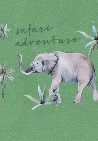 Groene stof met een gestileerde olifant en bladeren. Tekst leest "safari avontuur." Zachte textuur met gedetailleerde illustraties.