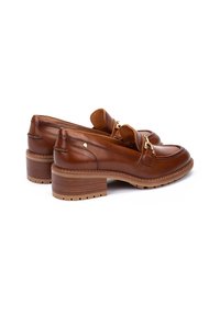 Mocasines de cuero marrón con punta redondeada, un pequeño tacón cuadrado, acentos decorativos de hardware dorado y una suela texturizada.