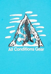 Turkos tyg med en bergsgraphic i svart och vitt med blå accenter. Texten nedan lyder "All Conditions Gear."