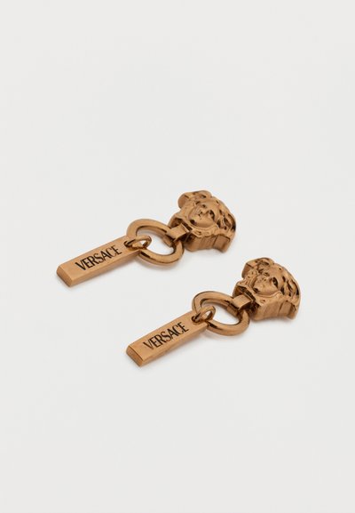 Σκουλαρίκια Versace σε χρυσό τόνο με καρφίτσες κεφαλής Μέδουσας συνδεδεμένες με ορθογώνιες πλάκες χαραγμένες με το γράμμα "VERSACE".