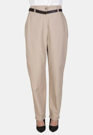 Pantaloni beige a vita alta con orli risvoltati, cintura nera, indossati con tacchi neri a punta e camicia bianca infilata.