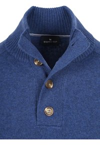 Pullover trui in diepblauwe brei met een geribbelde kraag. Voorzien van drie bronzen knopen bij de hals en een label met de tekst "STEPPIN' OUT."