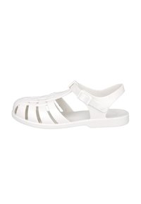 Sandal de plástico blanco con punta abierta, diseño superior trenzado, correa ajustable en el tobillo y plantilla texturizada. Estilo clásico y ligero.