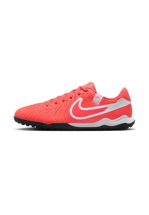 Zapatos de fútbol Nike en un vibrante color coral con acentos blancos. Presentan una parte superior texturizada, punta redonda y una suela exterior de goma negra resistente diseñada para ofrecer agarre.