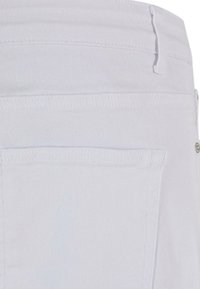 Jeans de mezclilla blanca con un acabado texturizado, que cuentan con bolsillos traseros y detalles de costura visibles. El diseño es simple y moderno.