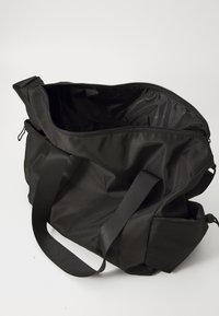 Fekete vászontáska nylon anyagból. Cipzáros záródással, széles pántokkal és belső zsebbel rendelkezik, sima, matt textúrával.